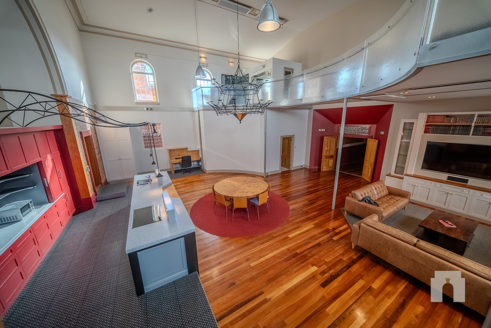 View from the mezzanine over the hall, with island bench, dining table and leather sofas below.
