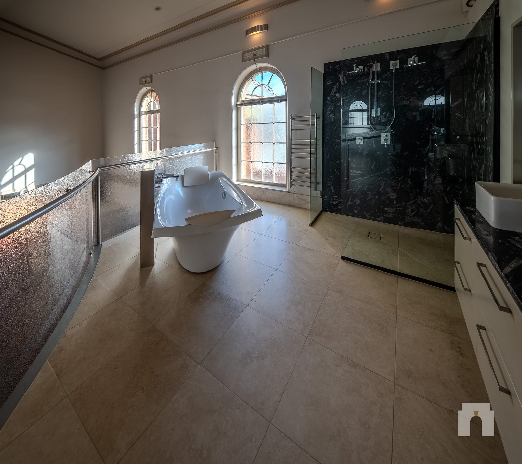 Tiled bathroom with freestanding bath, walk in shower with dark stone wall, and vanity.