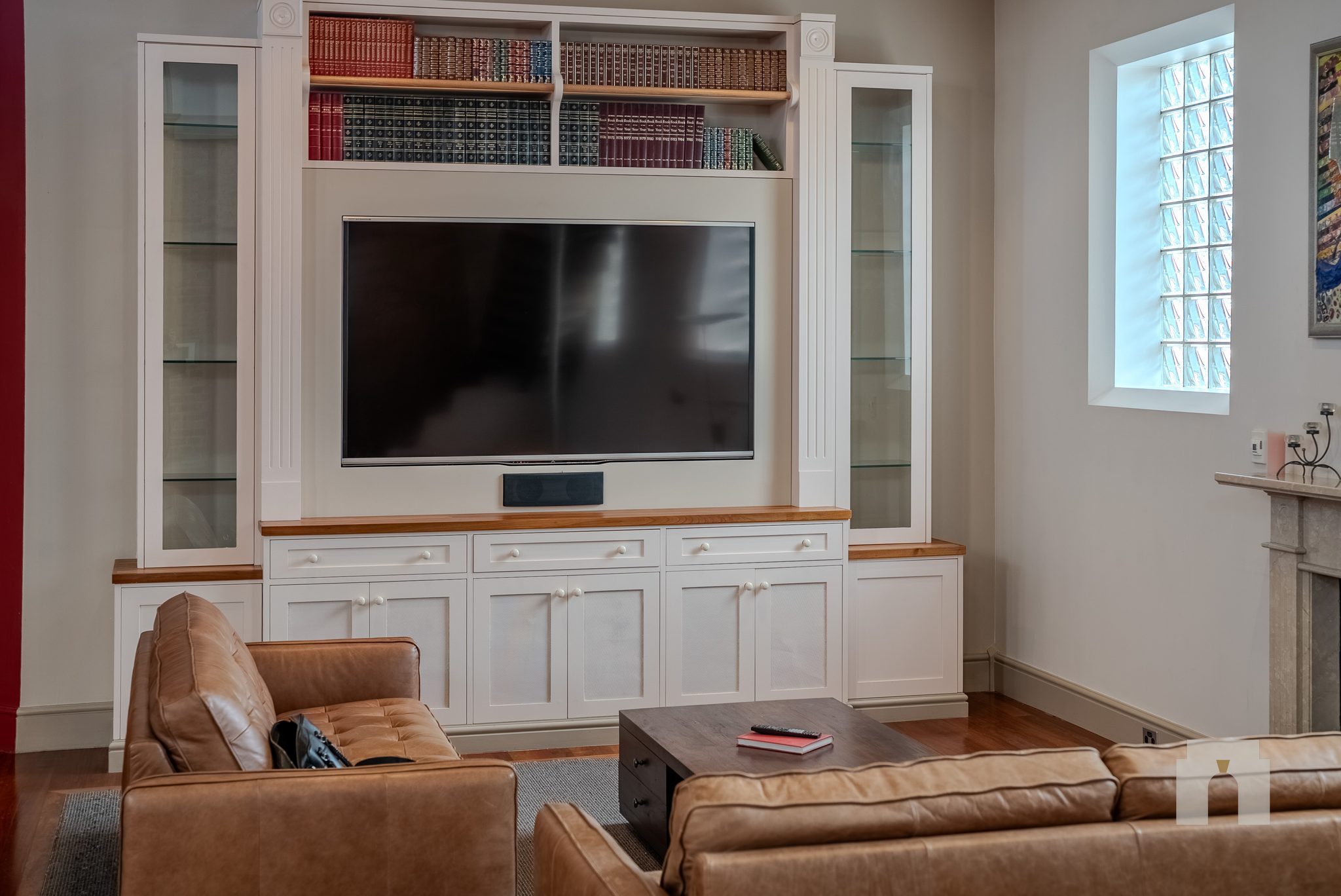 Seating area with leather sofas facing built-in joinery with bookshelves and a wall screen.