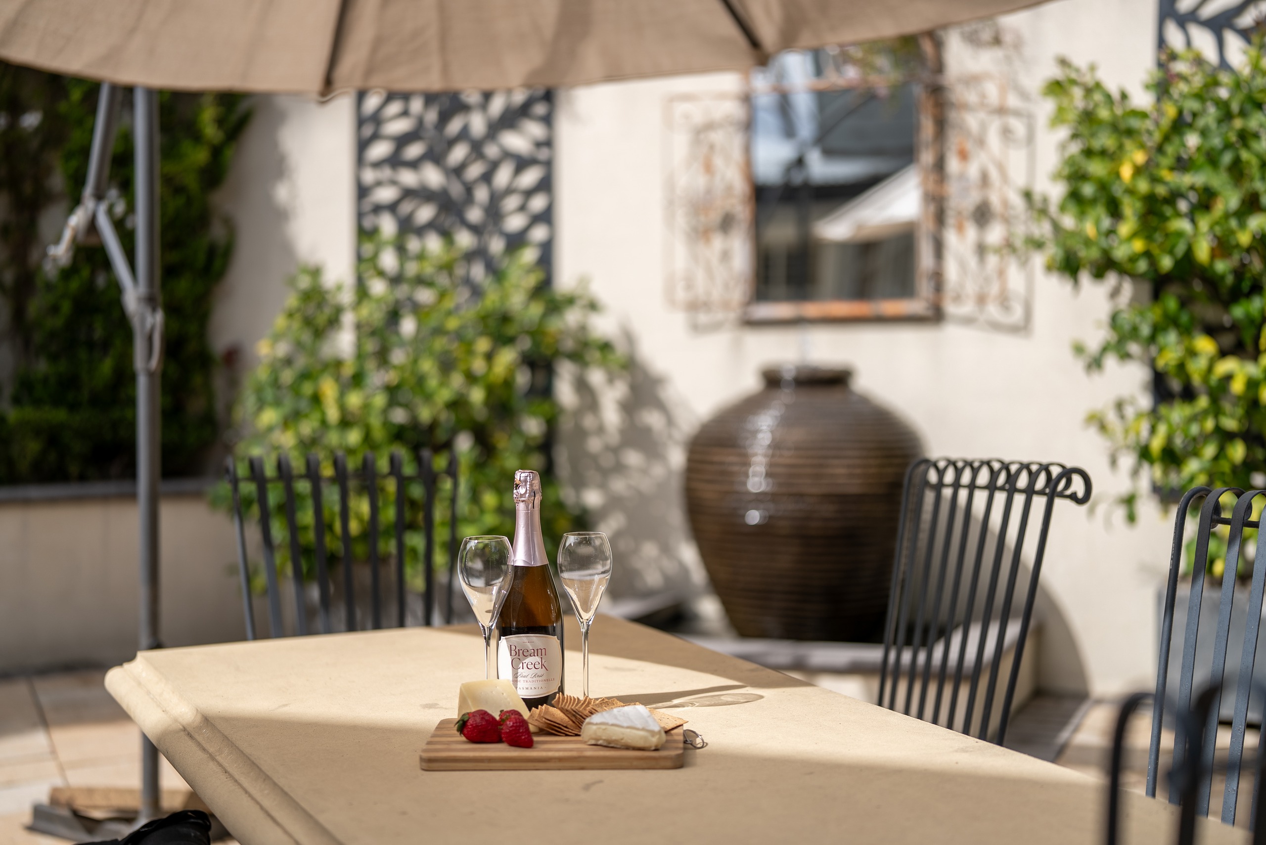 Champagne and a cheese board on the courtyard table, with the urn water feature behind.