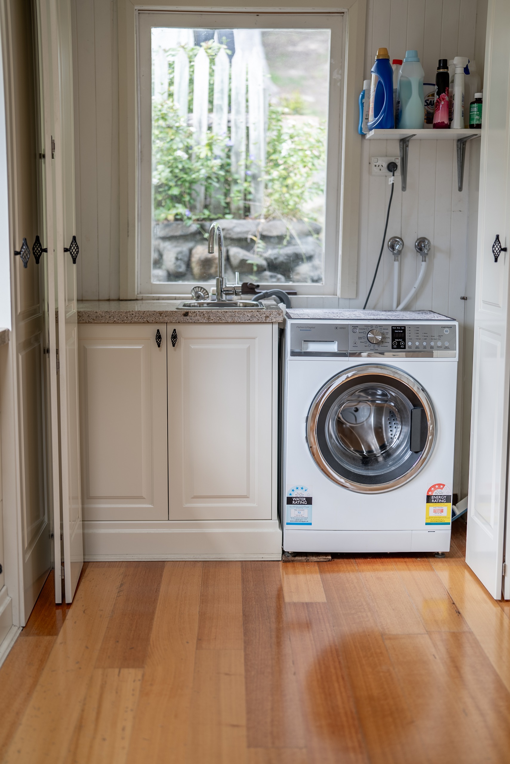 The laundry with a front-loading washing machine, cabinetry and a window to the garden.