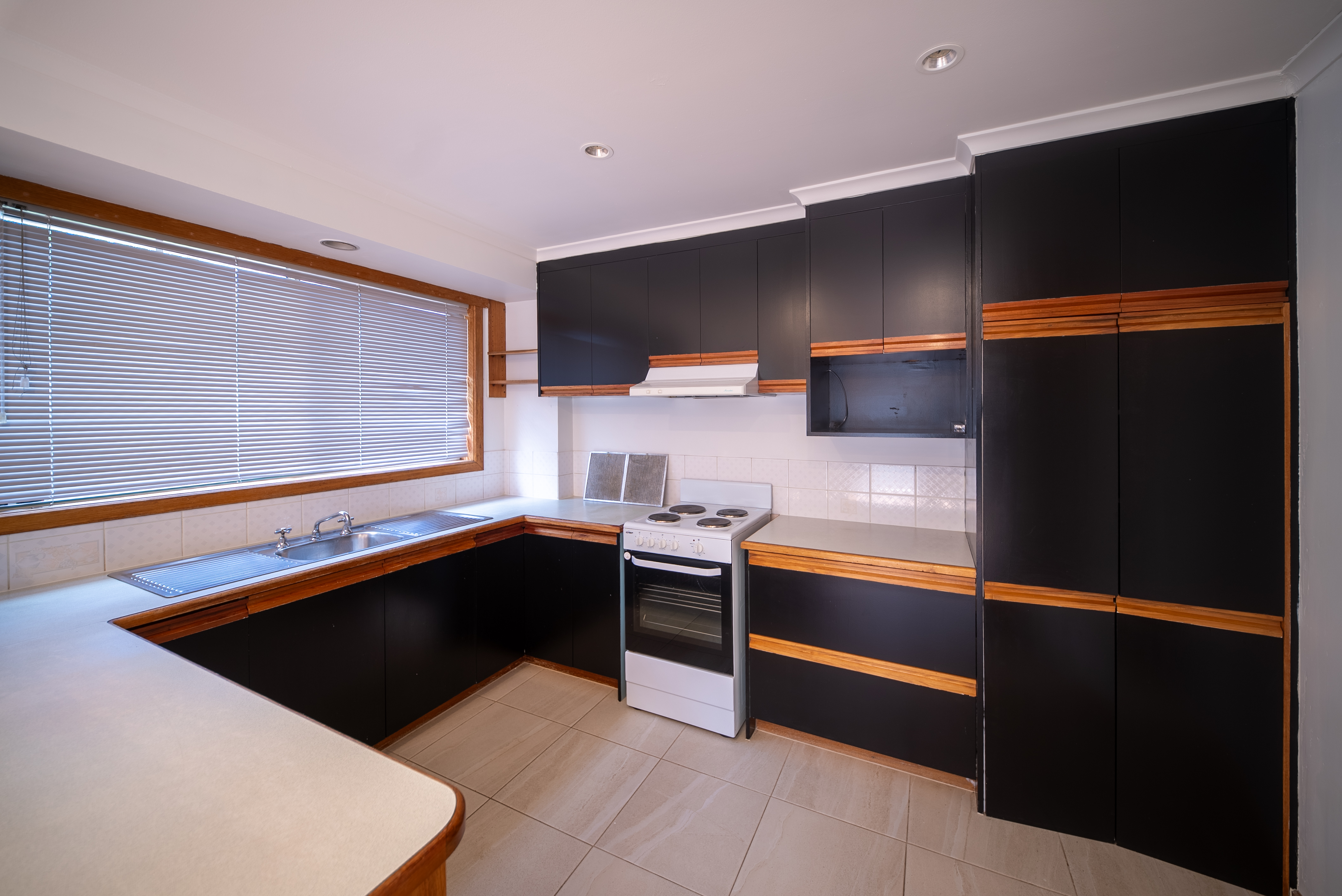 Kitchen with dark cabinetry, an upright electric oven and a window over the sink.