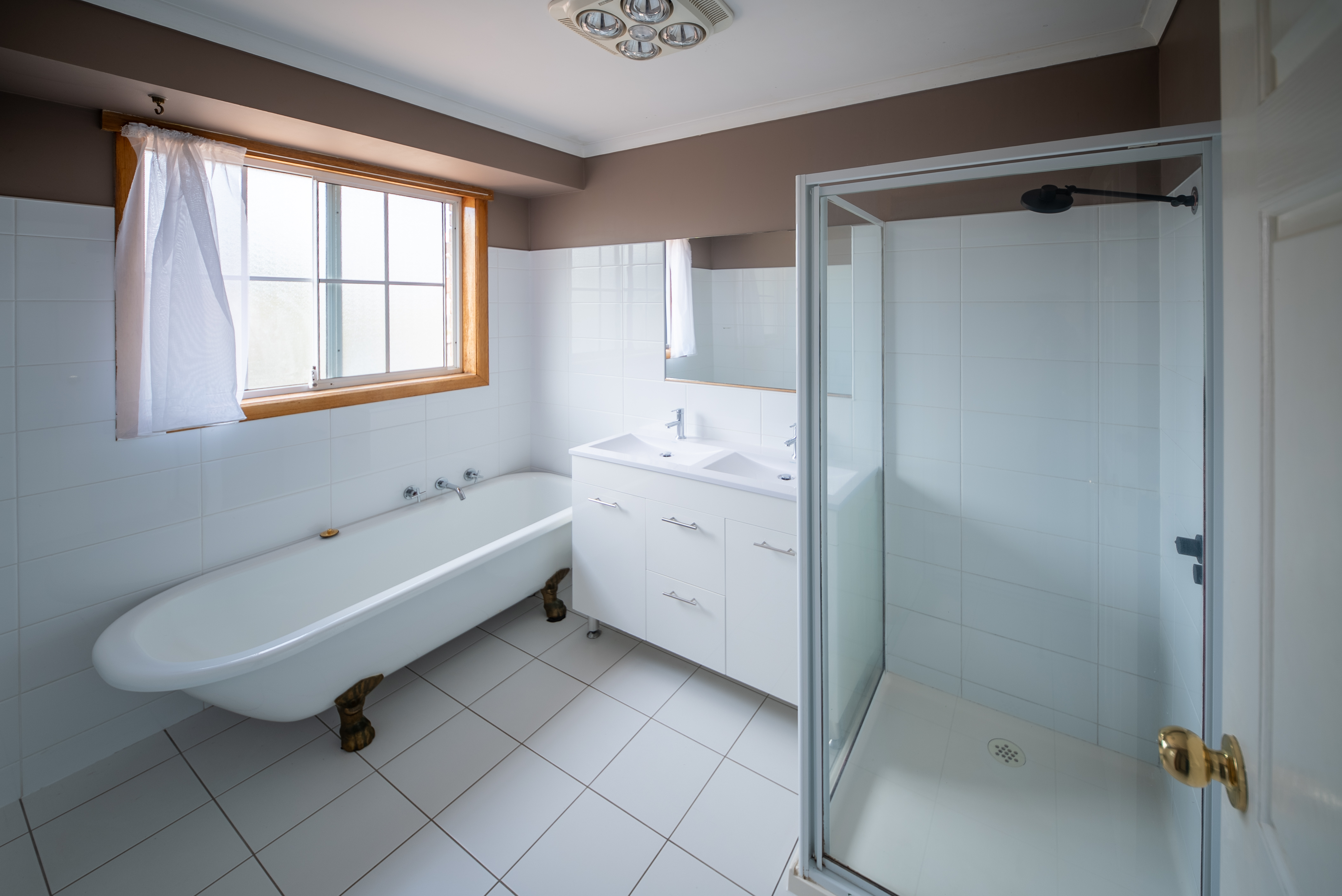 Main bathroom with a clawfoot bath, a glass-screened shower and a double vanity.