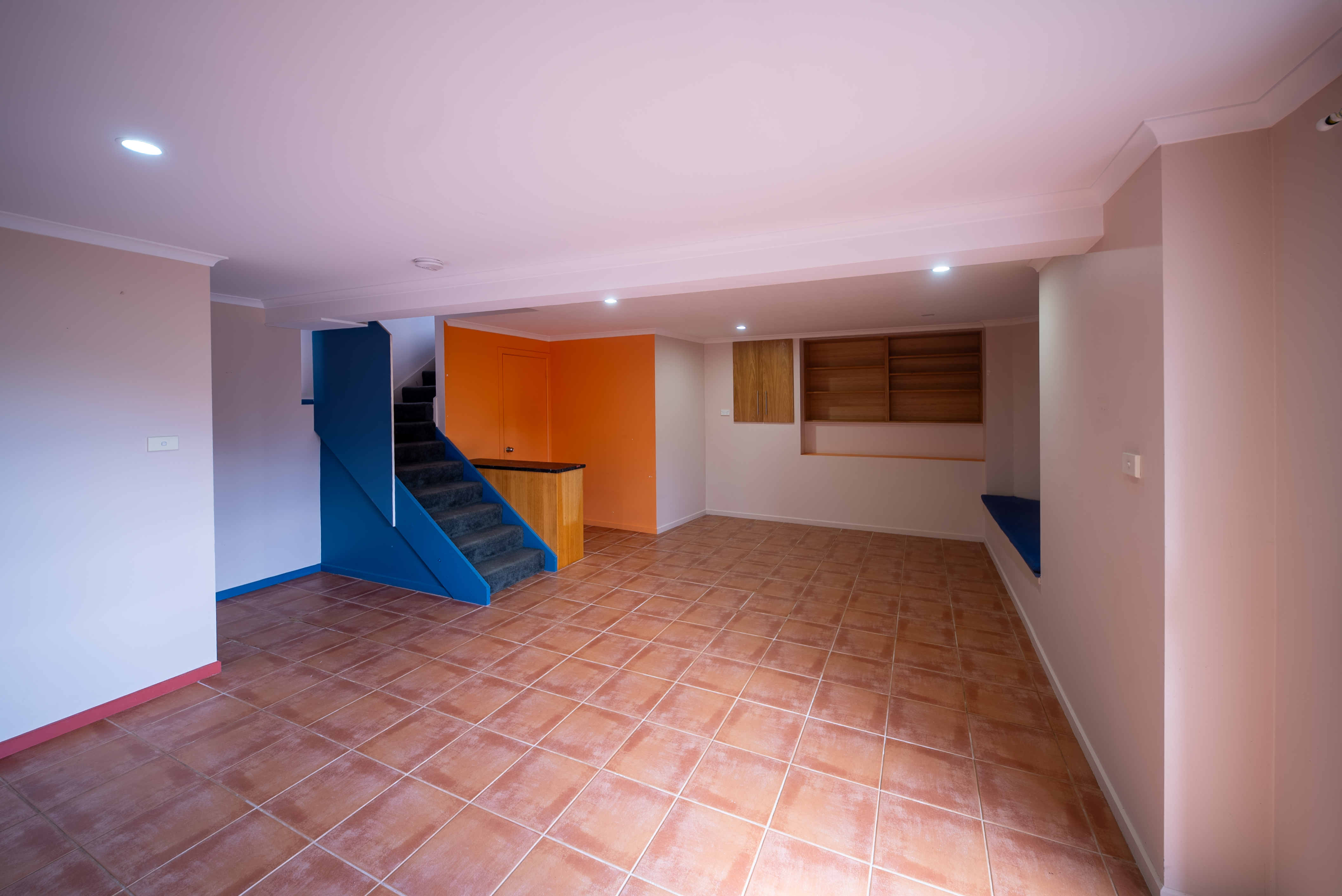 Downstairs rumpus room with a tiled floor, a bar area and stairs up to the main level.