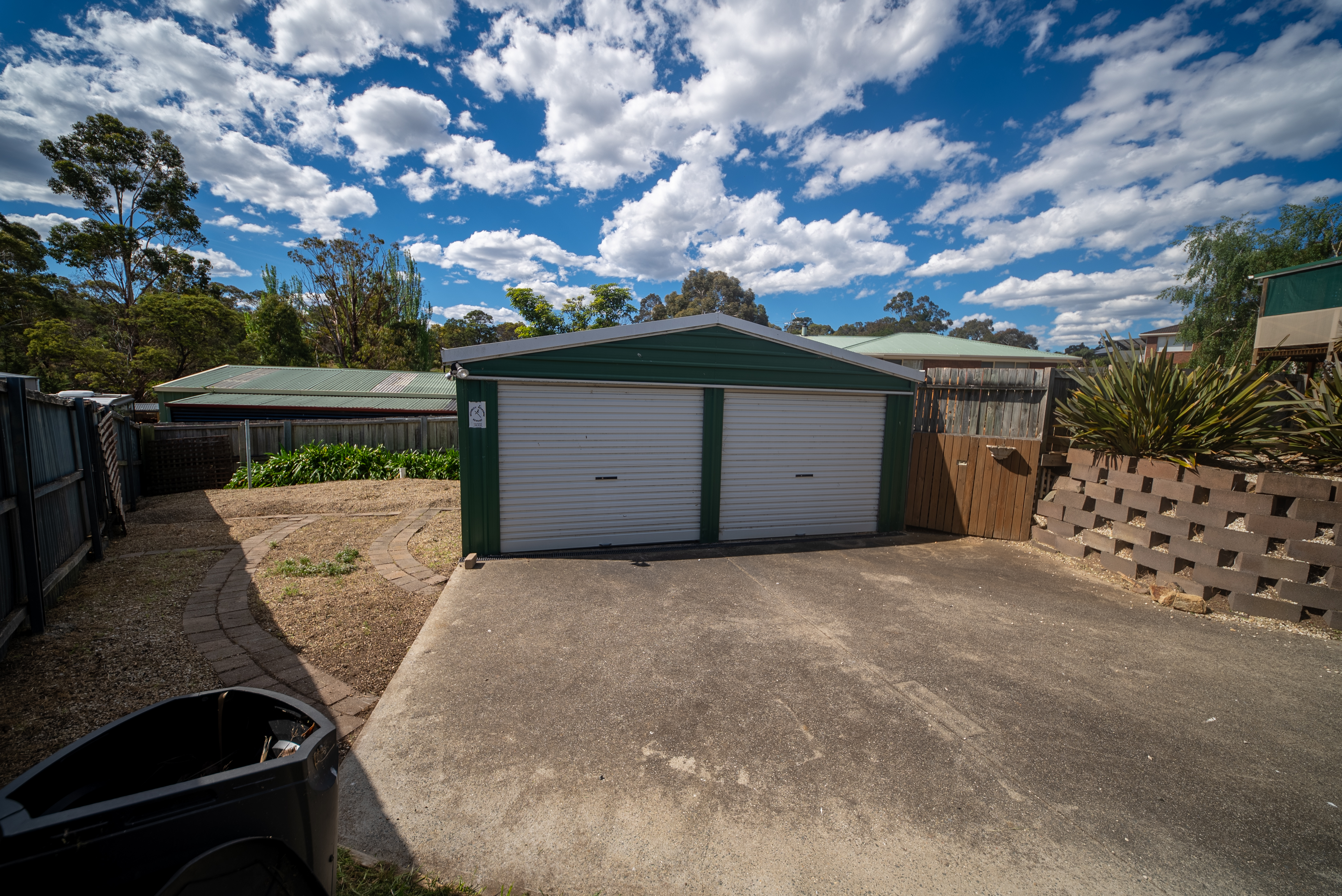 Detached double garage with two roller doors at the end of the driveway.