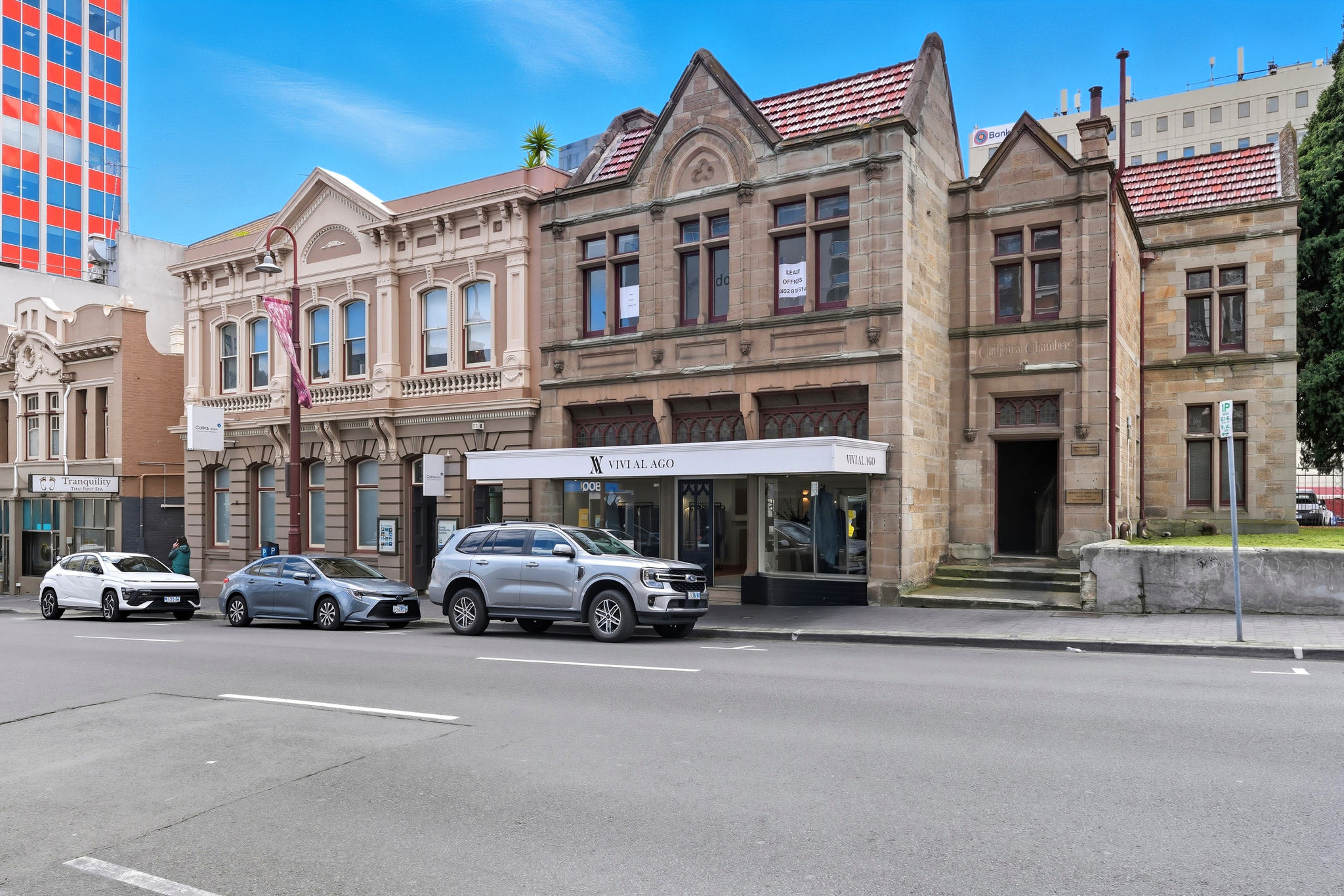 Sandstone and rendered heritage buildings on Murray Street, with a shop awning and cars parked at the kerb.