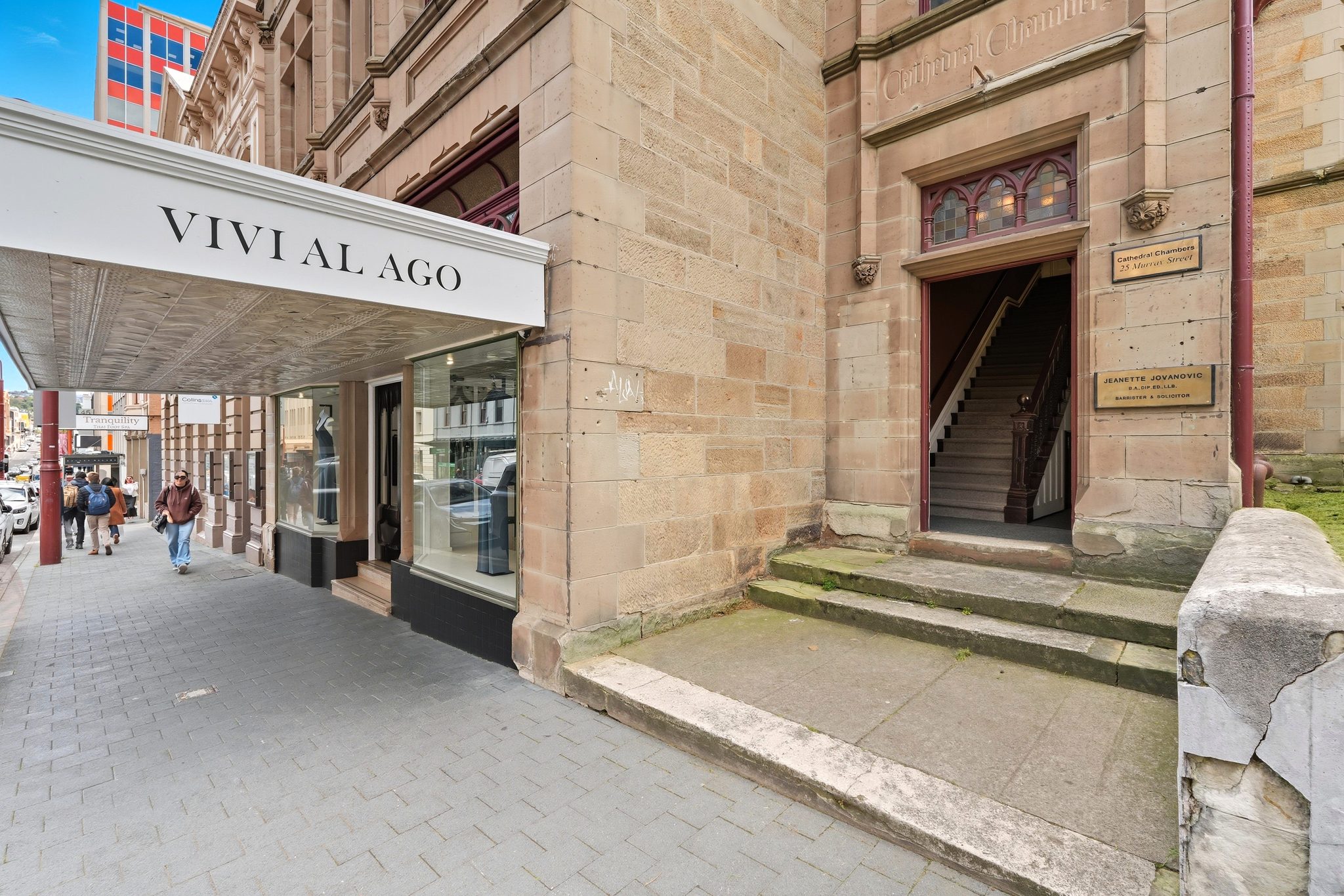 Sandstone entry with stone steps to an open doorway, a timber staircase inside and brass name plaques.