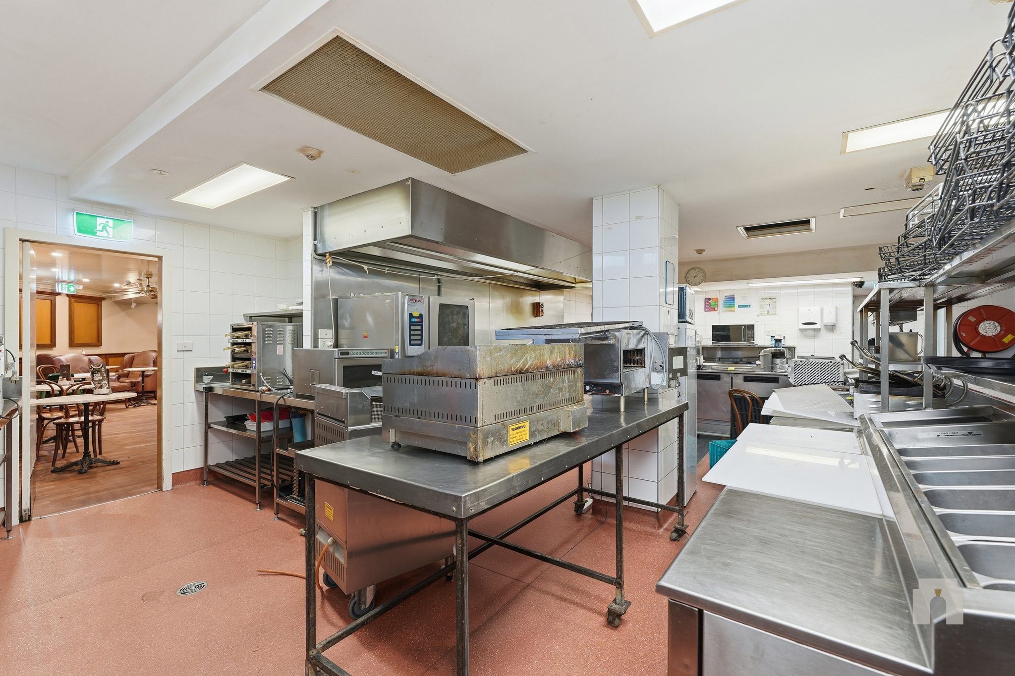 Kitchen with extraction canopy and stainless benches, doorway through to the dining room.