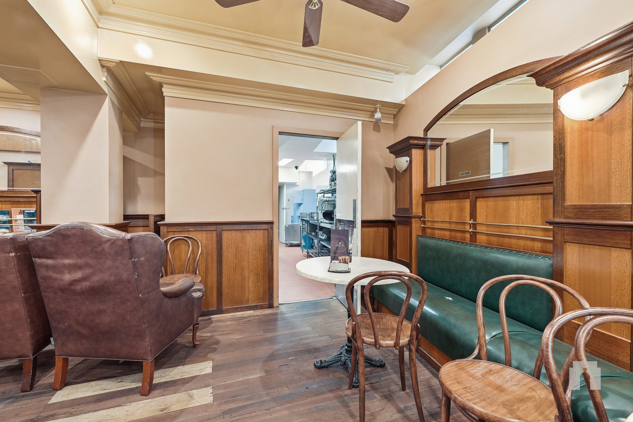 Booth seating with bentwood chairs and green banquette, doorway through to the kitchen.