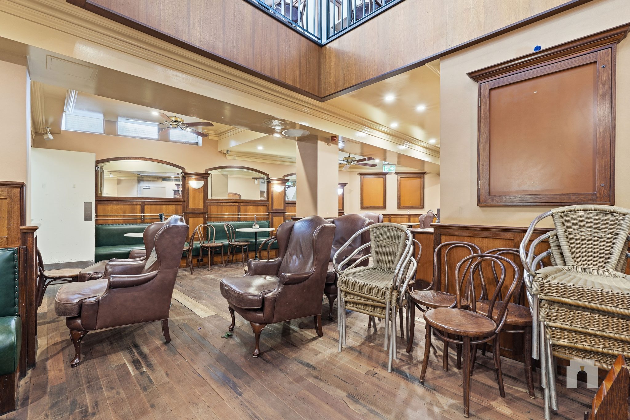 Dining room with leather chairs, and stacked wicker and bentwood chairs on the timber floor.