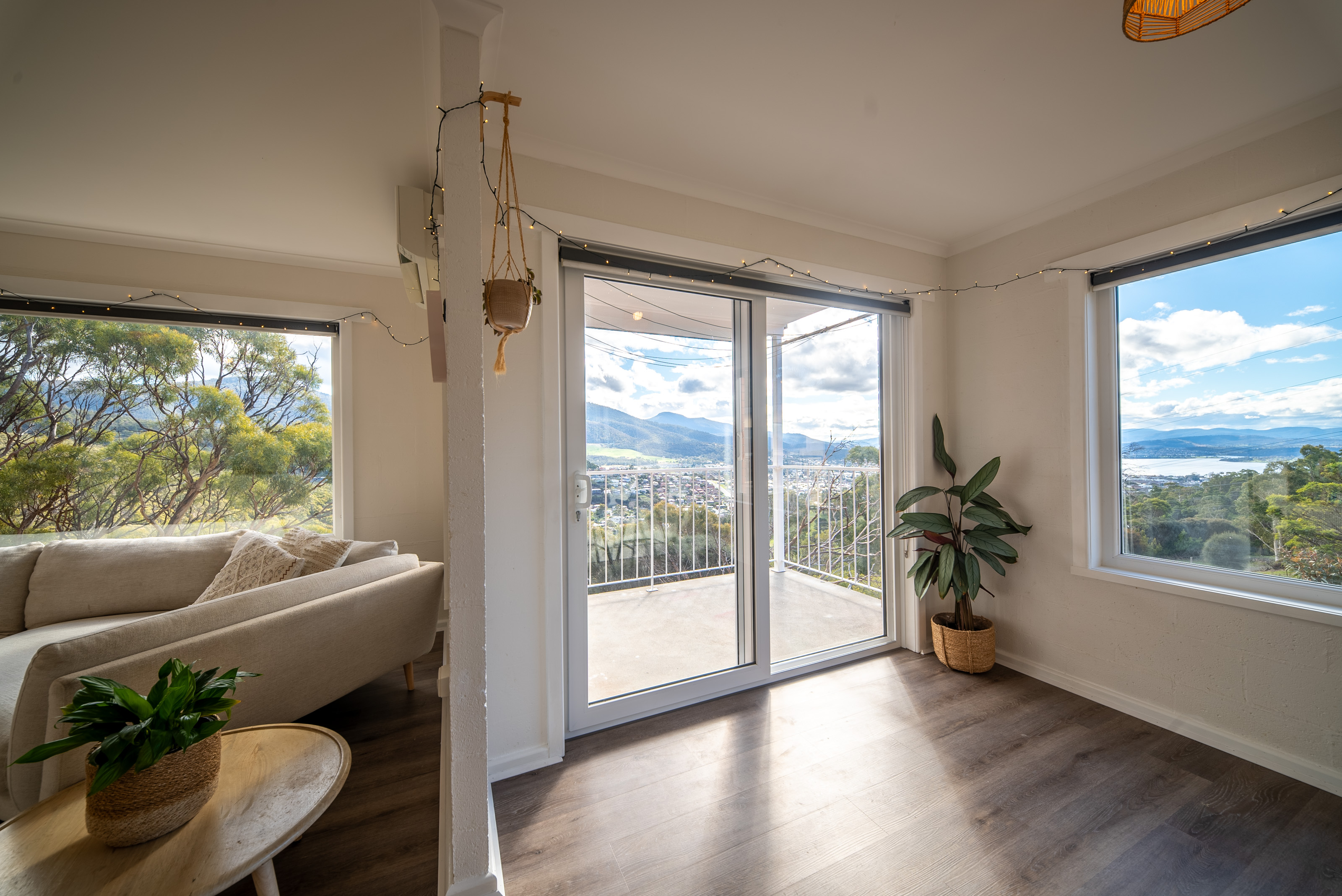 Corner of the living room with a sliding door and two windows looking over the valley to the mountains.