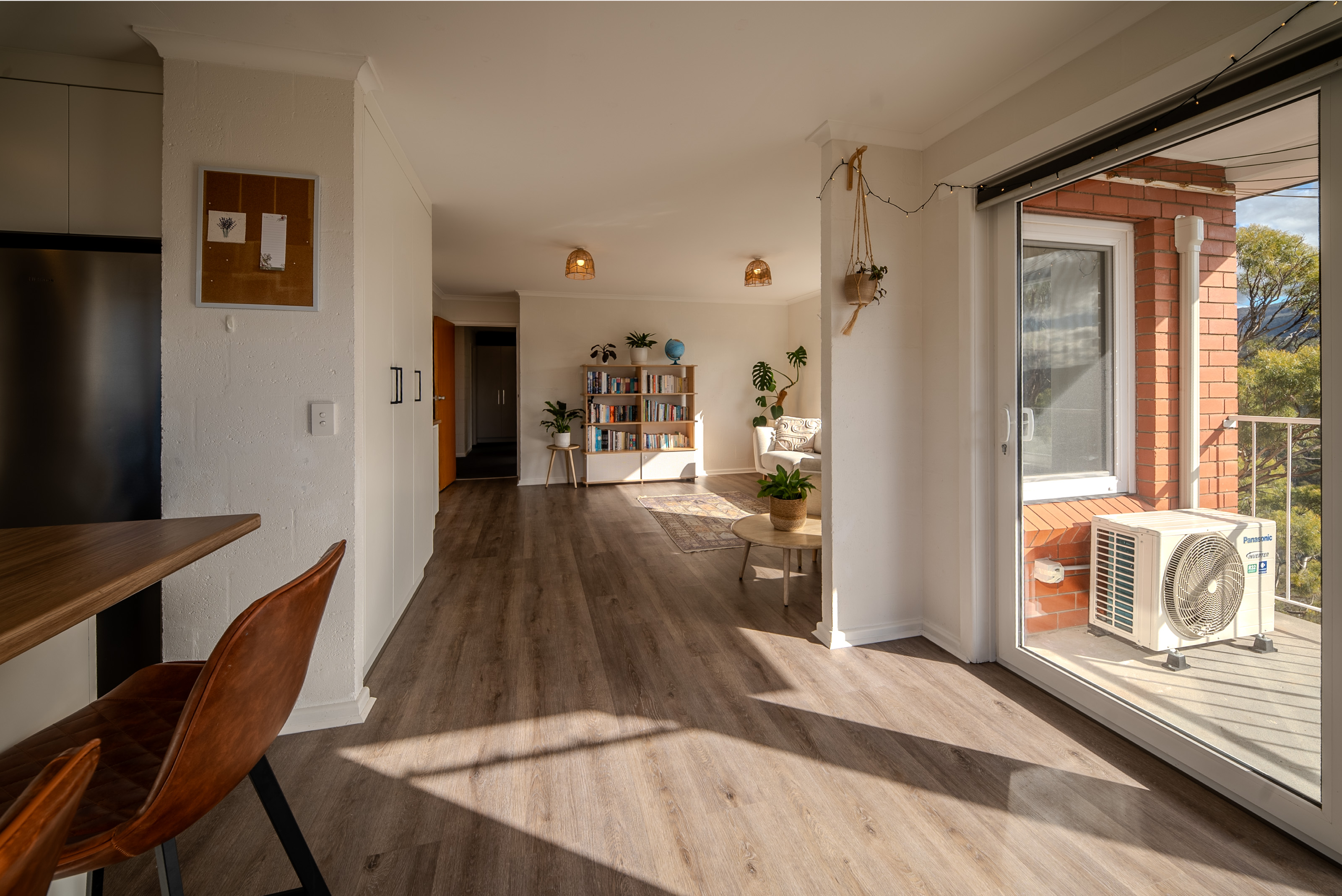 View from the kitchen along the living space to the bookshelves at the far end, with the balcony door to the right.