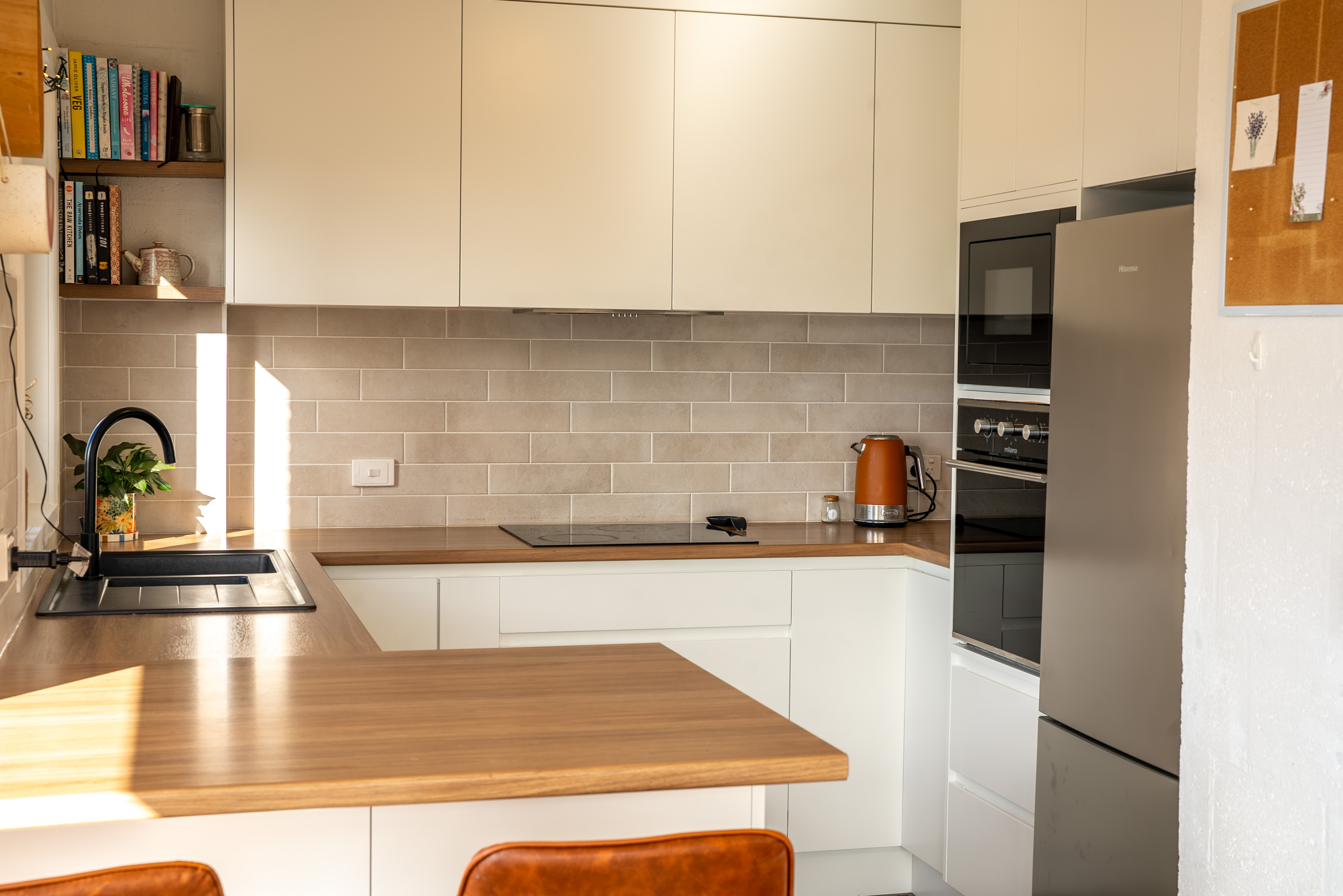 Kitchen with white cabinetry, a cooktop, a wall oven and a tiled splashback.