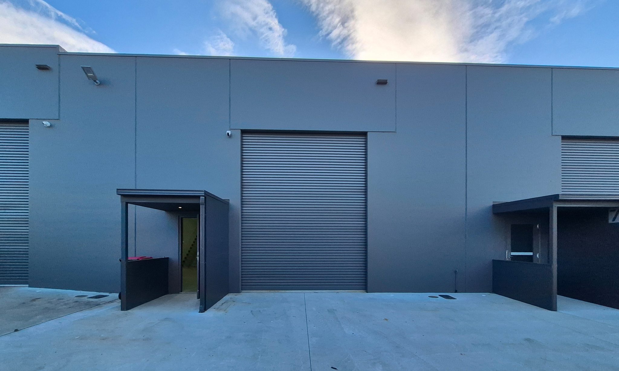 Unit frontage on Cessna Way with a roller shutter door, covered entry door, and concrete hardstand.