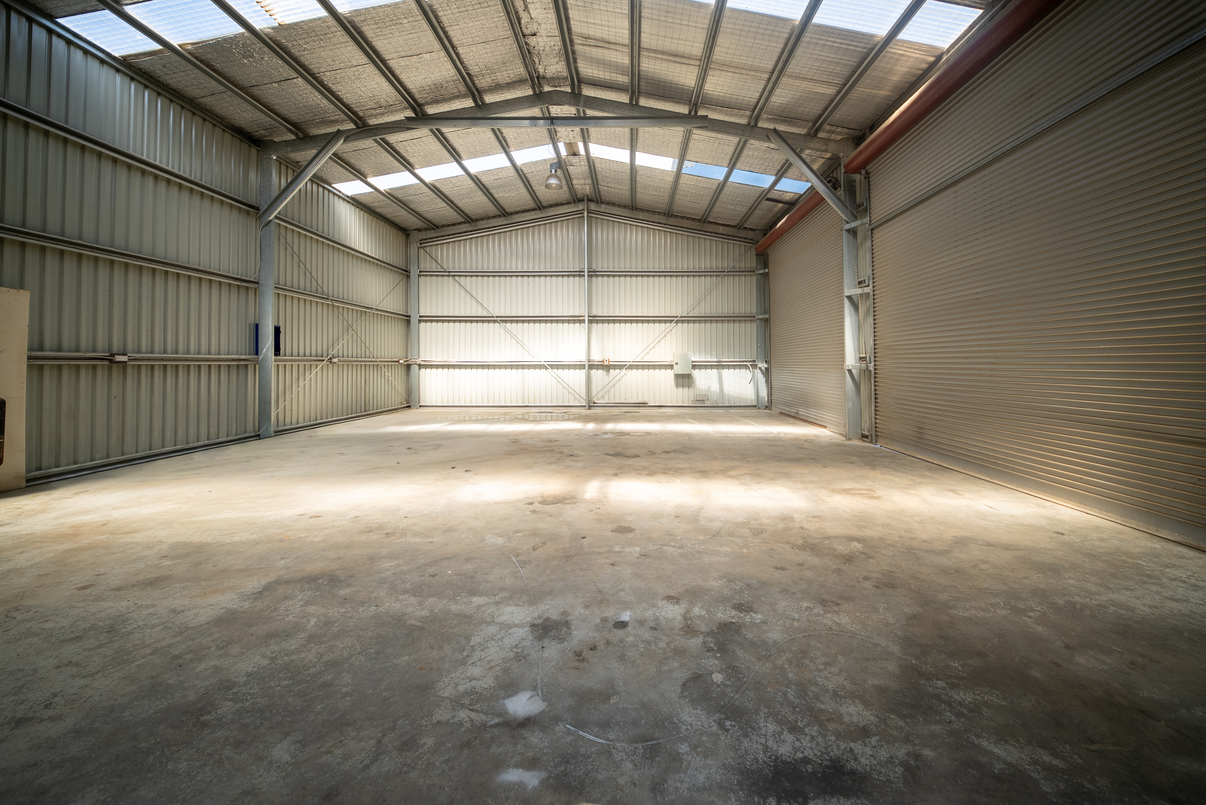 Open clear-span floor with a steel portal frame, insulated roof and natural light from clear roof sheets.