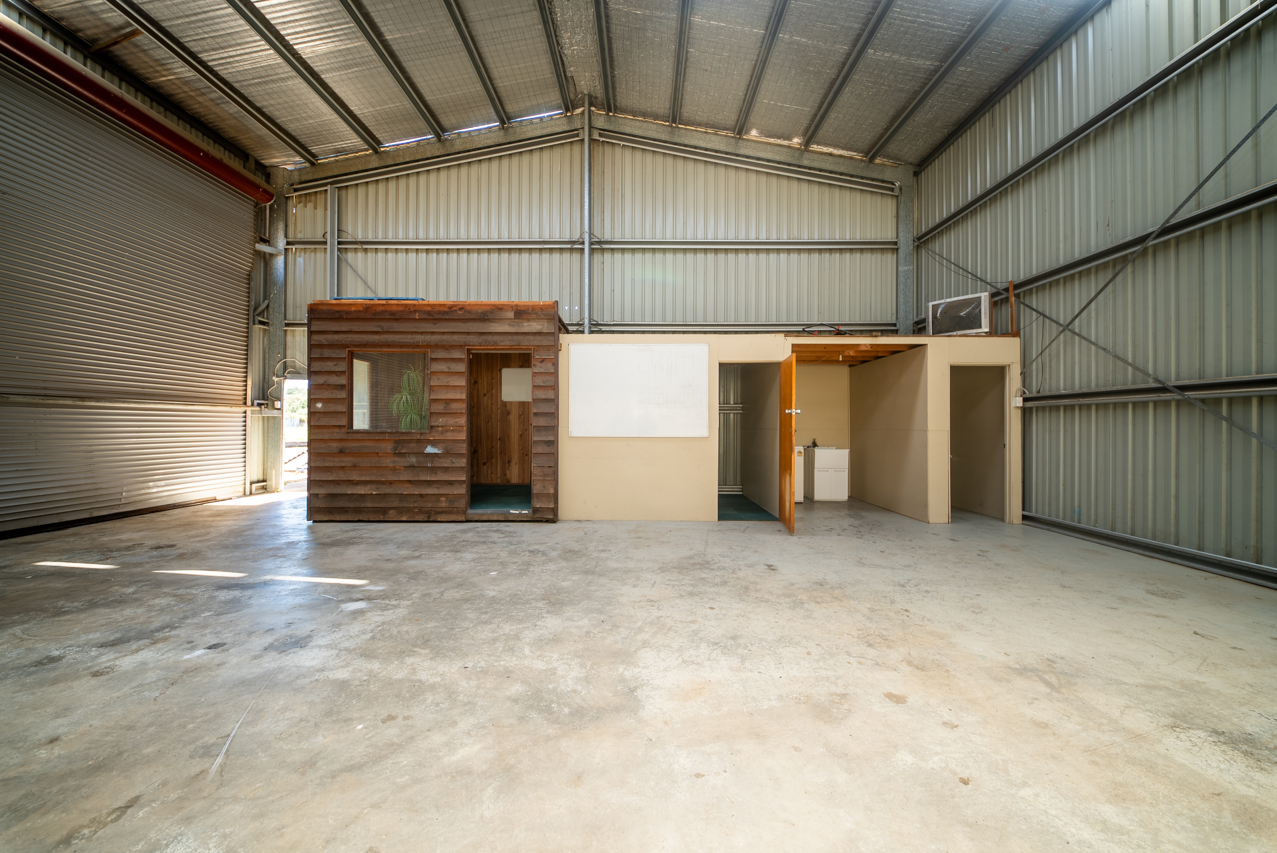 Timber-clad site office and lined rooms at one end of the warehouse floor.