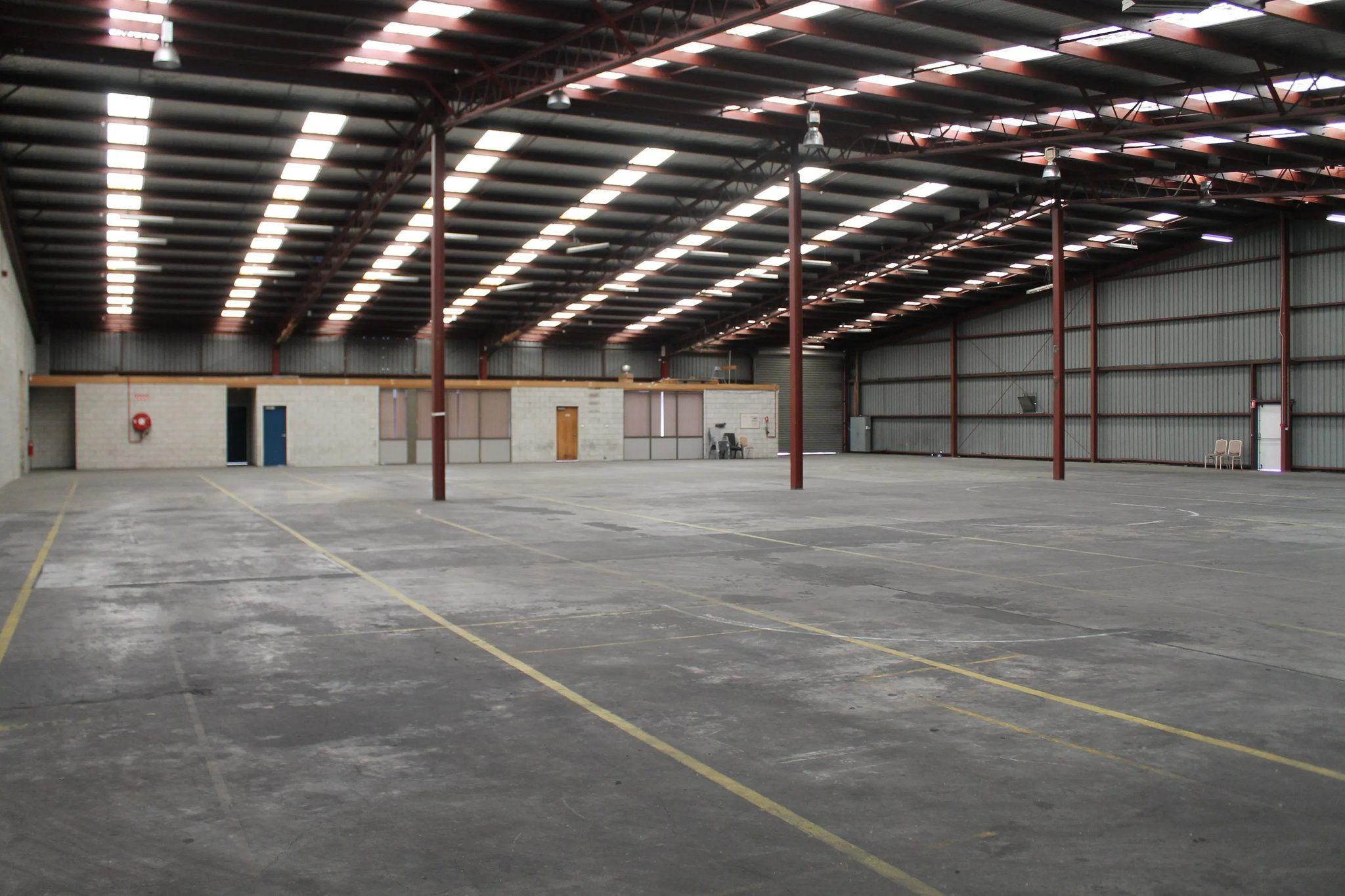Warehouse floor marked with yellow lines, with a blockwork office wall and roller shutter at the far end.